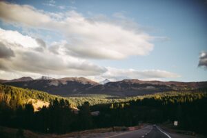 A scenic view of a Colorado mountain range with a highway road in the foreground